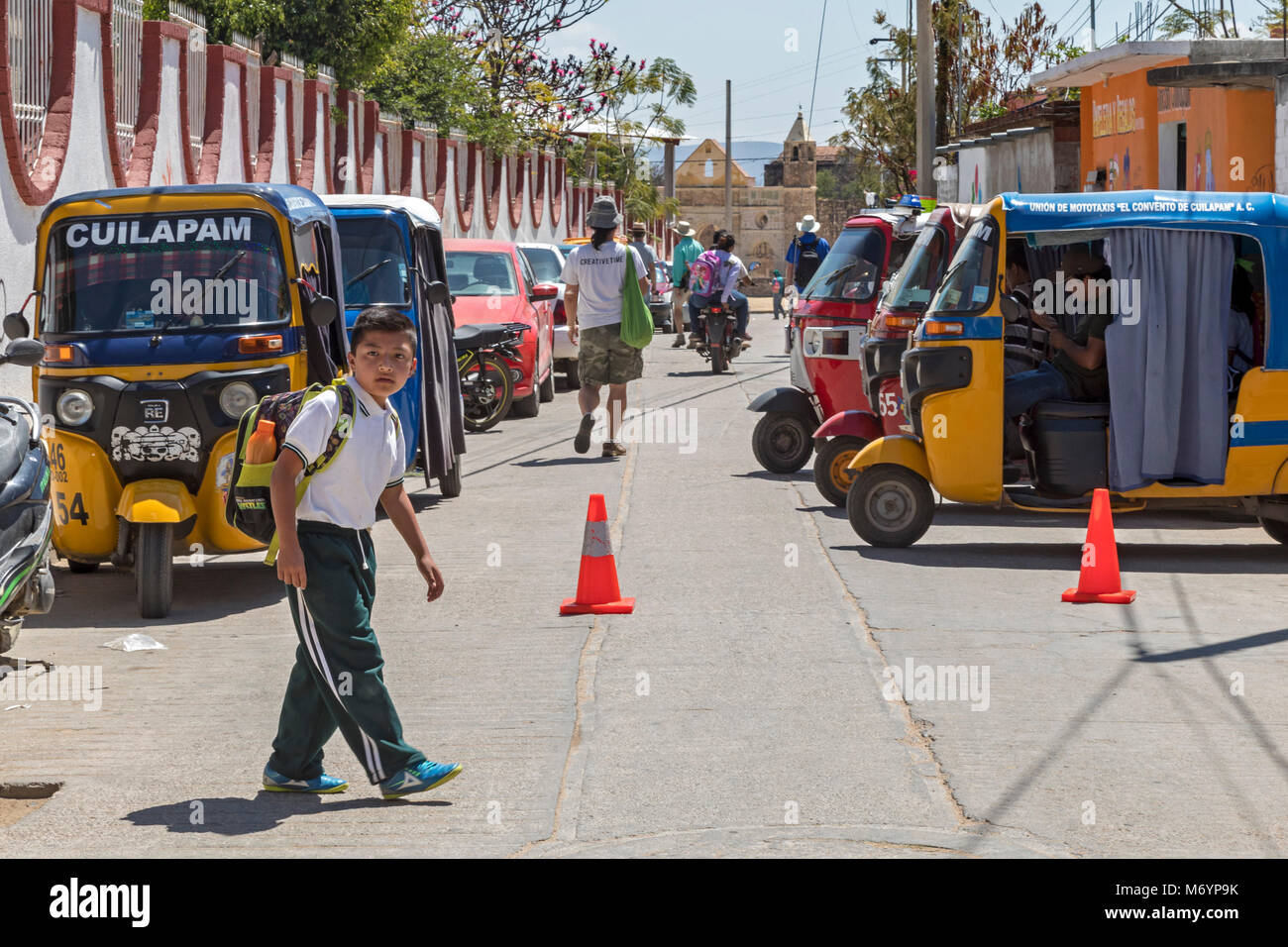 Cuilapam de Guerrero, Oaxaca, Mexique - Un garçon marche à la maison de l'école, cours des trois roues, des taxis de la ville. Les taxis sont très communes dans les villes d'Oaxaca ; Banque D'Images