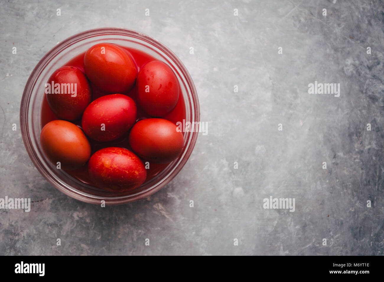 Ensemble de six de couleur rouge à l'intérieur d'un bol en verre pour les vacances de Pâques, la coloration avec teinte rouge les oeufs sur un fond de béton gris Banque D'Images