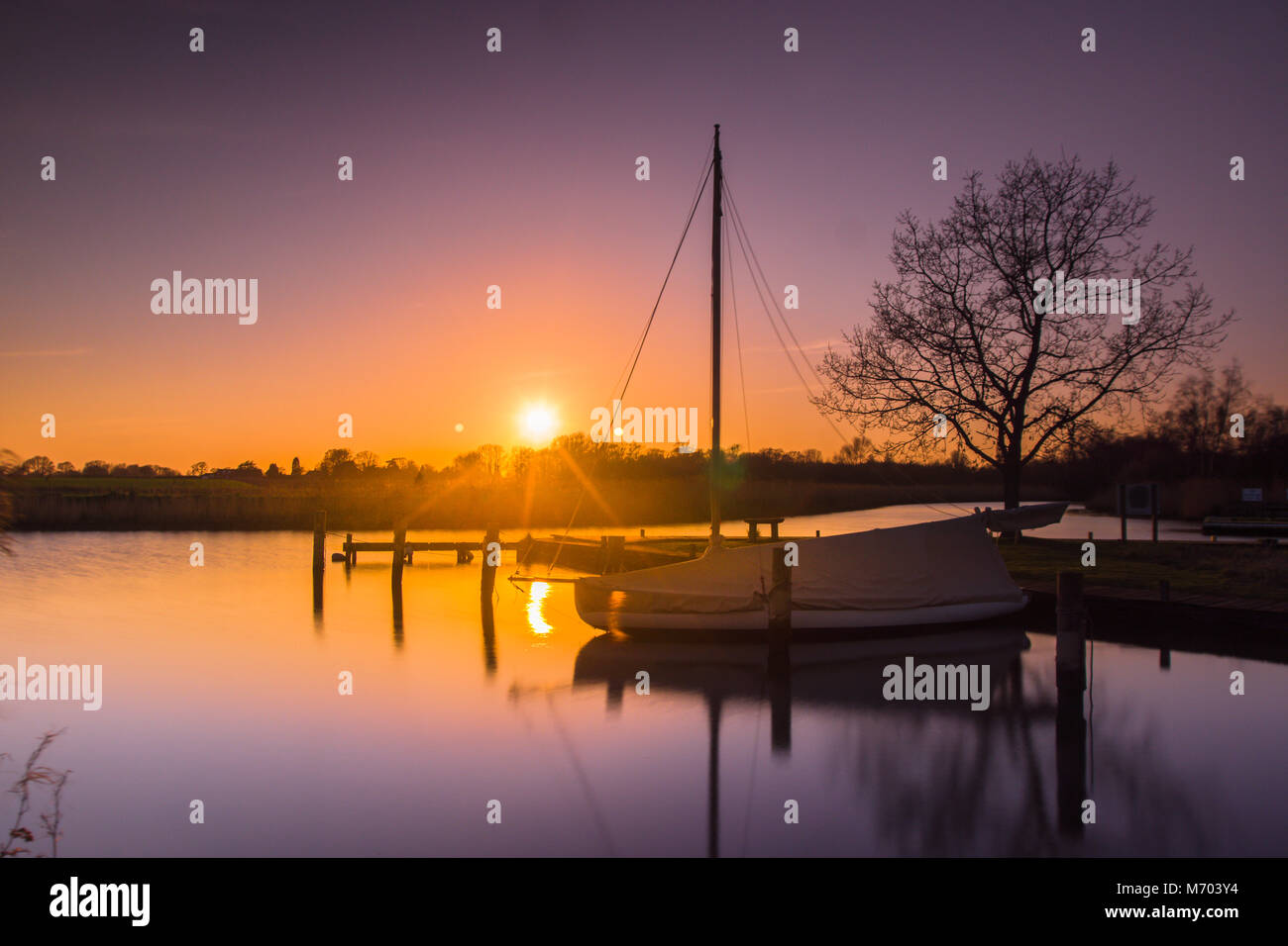 Coucher du soleil avec un bateau à voile au premier plan sur un jour d'été calme Banque D'Images