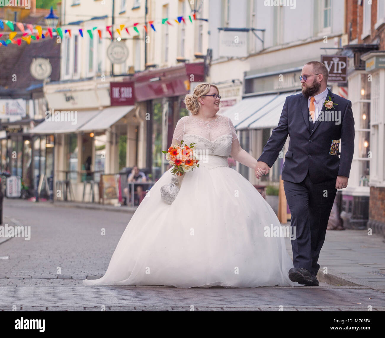 Couple nouvellement marié marchant dans la rue du soleil, Hitchin, Herts, UK Banque D'Images