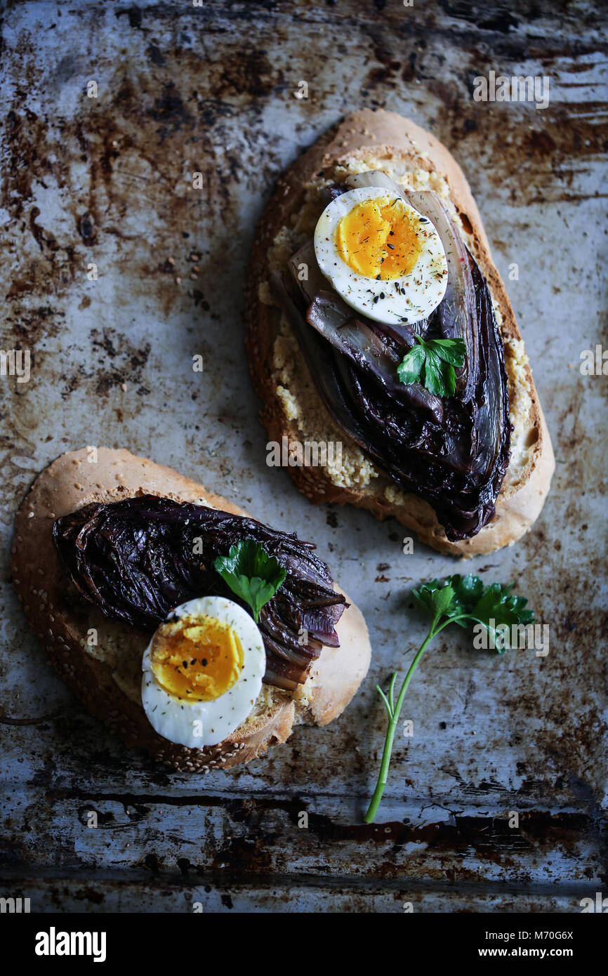 La chicorée rouge braisé crostini avec hoummos, oeuf mollet et épices Banque D'Images