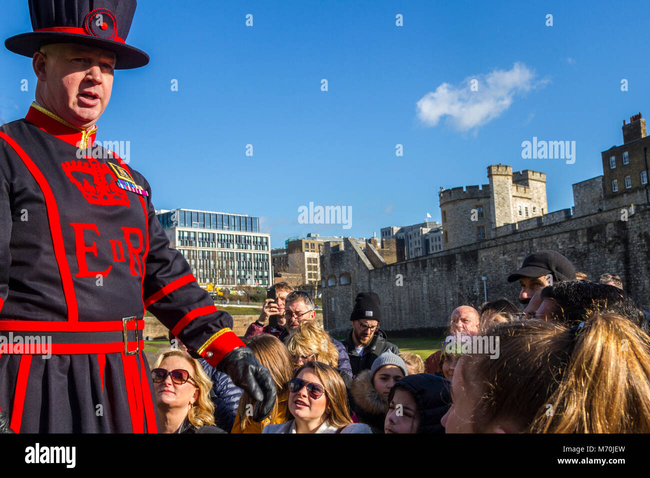 Le Beefeater chargé d'un circuit de foule de touristes à la Tour de Londres, l'accueil des joyaux de la Couronne, Tour de Hil, Londres UK London beefeater uniforme guide Banque D'Images