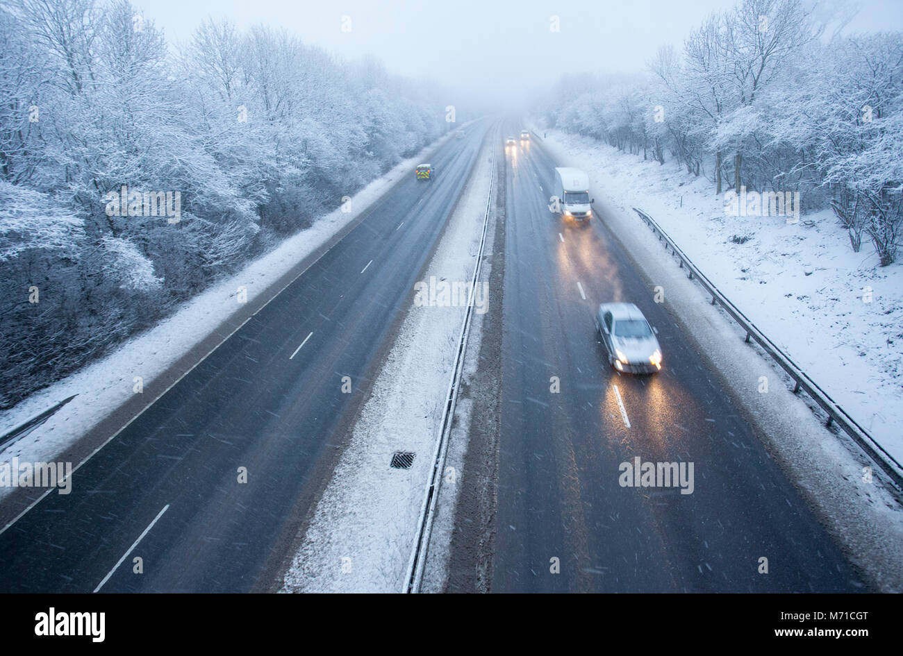 Les véhicules circulant le long d'un chemin couvert de neige A55 lorsqu'il passe dans Flintshire dans le Nord du Pays de Galles tôt le matin avec des chutes de neige et des températures de gel, ce qui rend difficile et dangereux l'hiver, Flintshire, Galles, Royaume-Uni Banque D'Images