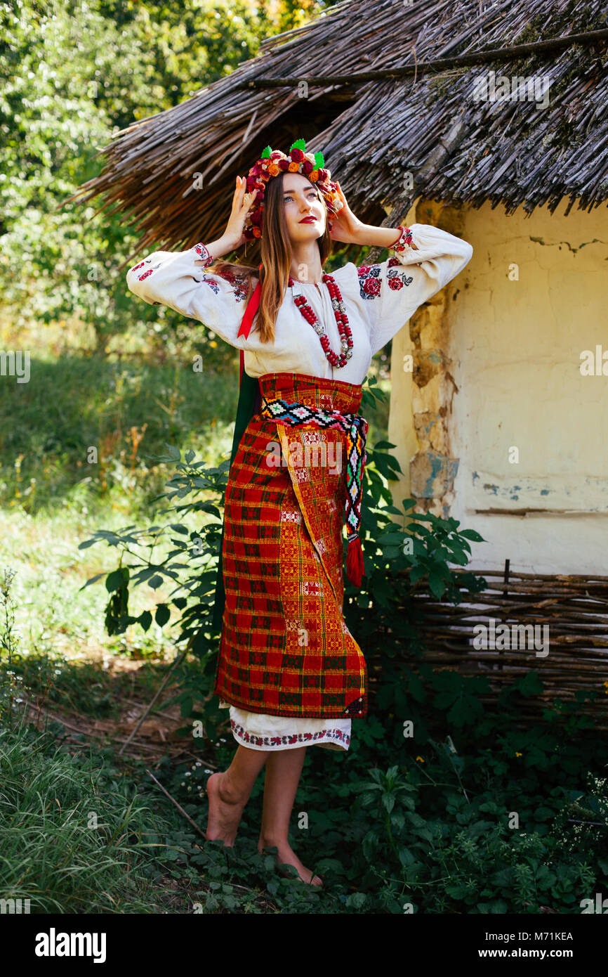 Belle jeune fille ukrainienne dans les vêtements nationaux brodé sur une cabane en bois à l'été Banque D'Images