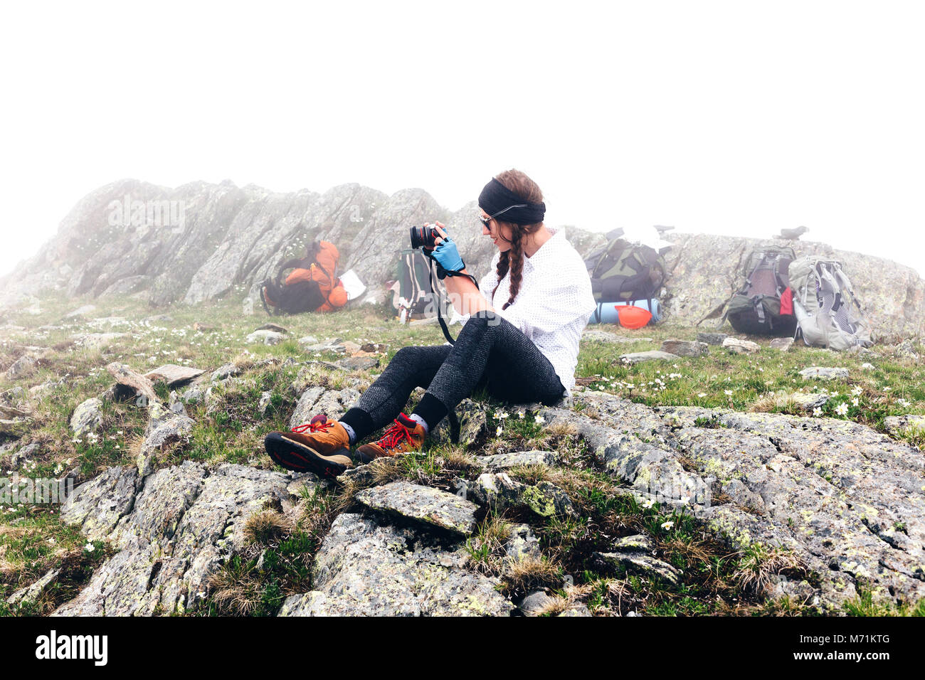 Une jeune fille se rend dans les montagnes pour prendre des photos avec un appareil photo, sac à dos de camping arrière-plan. Le concept de l'aventure, style de randonnées. Banque D'Images