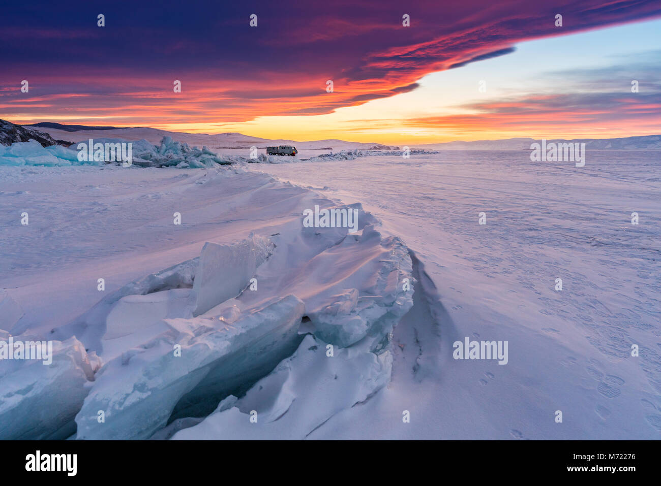 Paysage d'hiver dans le coucher du soleil, fissuré lac gelé recouvert de neige au lac Baikal en Russie avec beau coucher de soleil ciel Banque D'Images