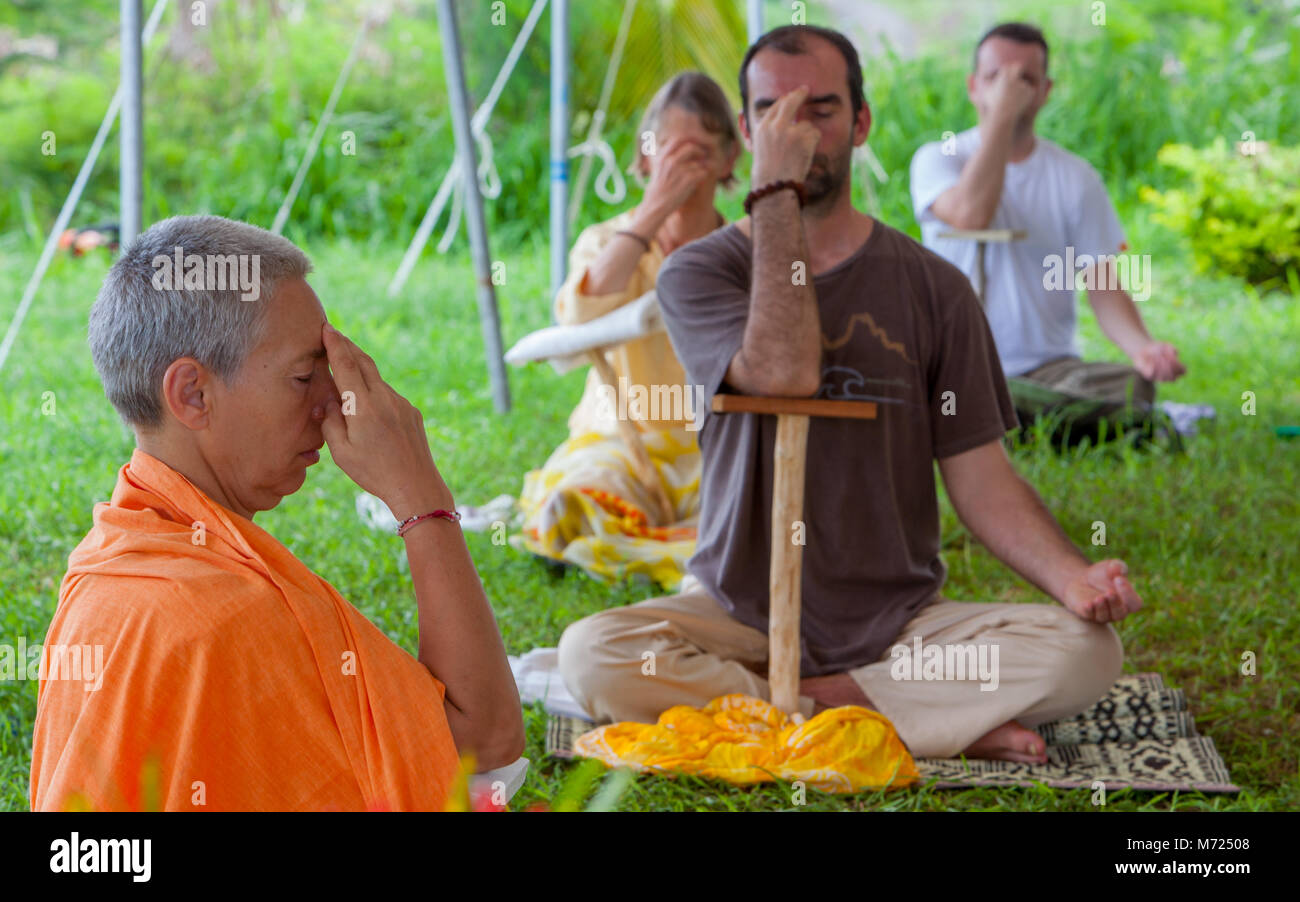 Des gens pratiquant la respiration yogique technique appelée pranayama l'aide de support stick Danda en retraite de yoga sur l'île de Fidji. Trois jeunes directeurs est enseignant Banque D'Images