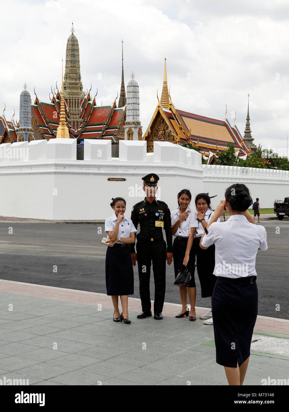 Les jeunes filles qui photo avec un officier de l'armée thaïlandaise avec le Grand Palais de Bangkok dans l'arrière-plan Banque D'Images