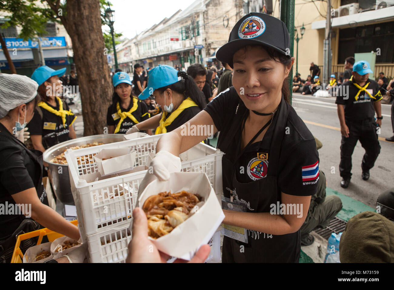 Une jeune fille bénévole offrant gratuitement de la nourriture à un participant à la crémation royale du roi thaïlandais à Bangkok Banque D'Images