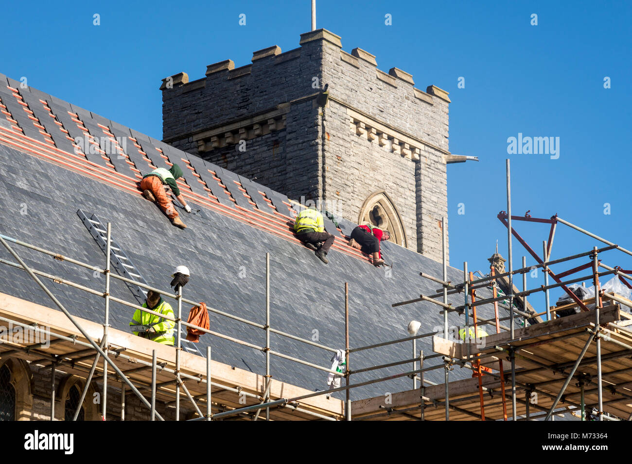 Refaire une toiture pendant que le soleil brille. La toiture de l'église All Saints à Barry, Le Pays de Galles à réparer par une belle journée ensoleillée sous un ciel bleu Banque D'Images