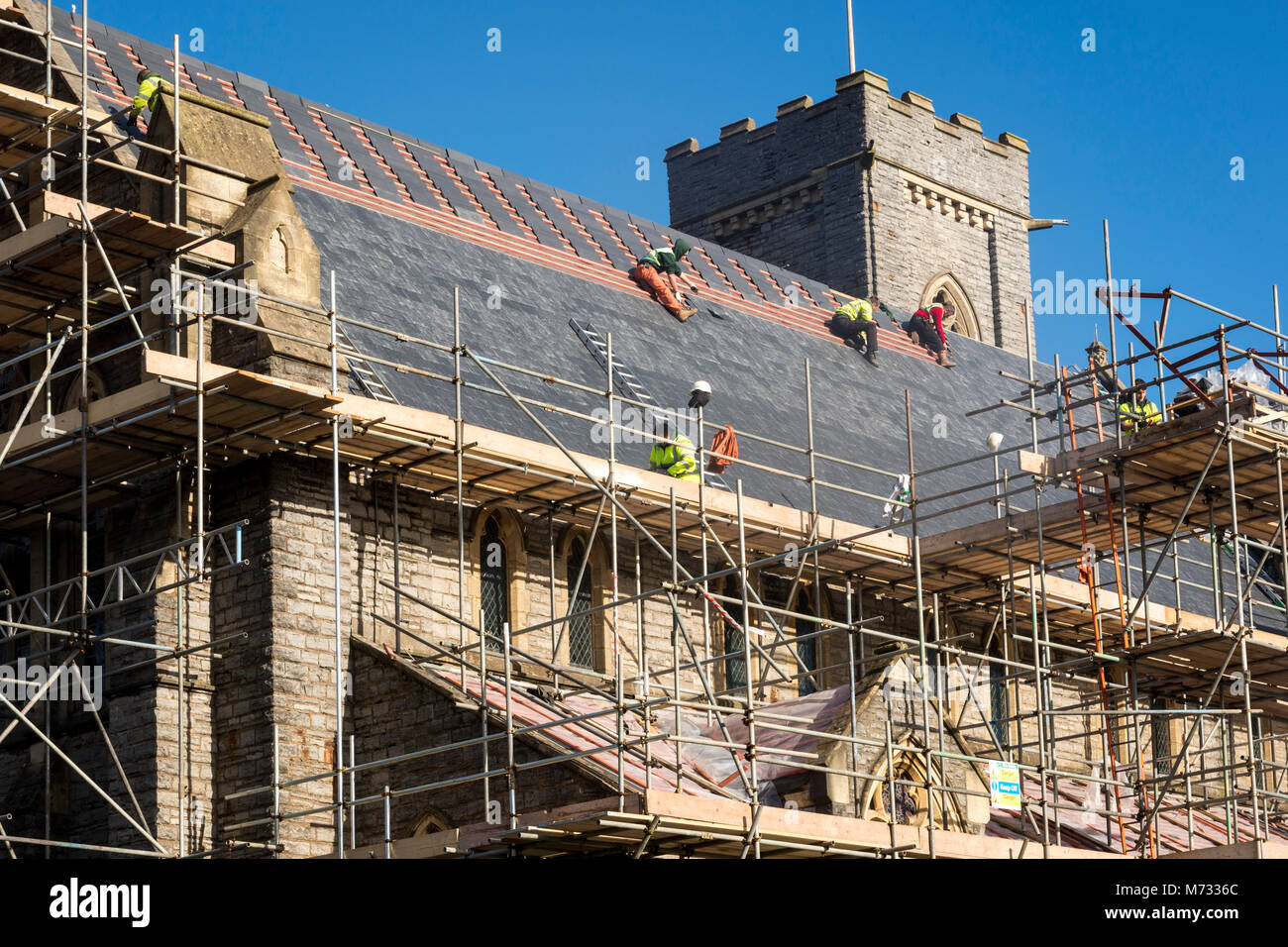 Refaire une toiture pendant que le soleil brille. La toiture de l'église All Saints à Barry, Le Pays de Galles à réparer par une belle journée ensoleillée sous un ciel bleu Banque D'Images