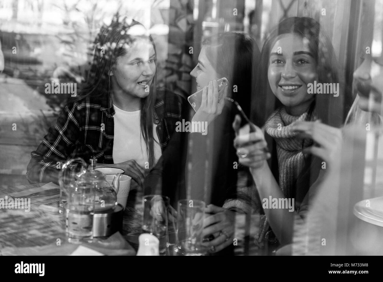 Friends enjoying coffee ensemble dans un café vue à travers le verre avec des réflexions Banque D'Images