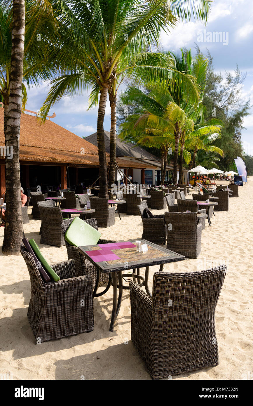 Beach café avec des tables et des chaises sur le sable au milieu des palmiers dans le soleil clair sans que les gens Banque D'Images