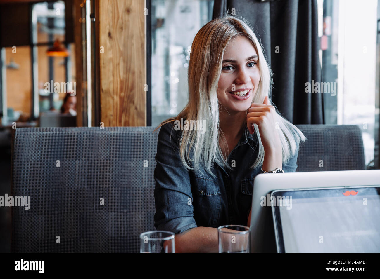 Un beau blond businesswoman dans une chemise en jean est assis dans un restaurant et communique avec ses amis Banque D'Images