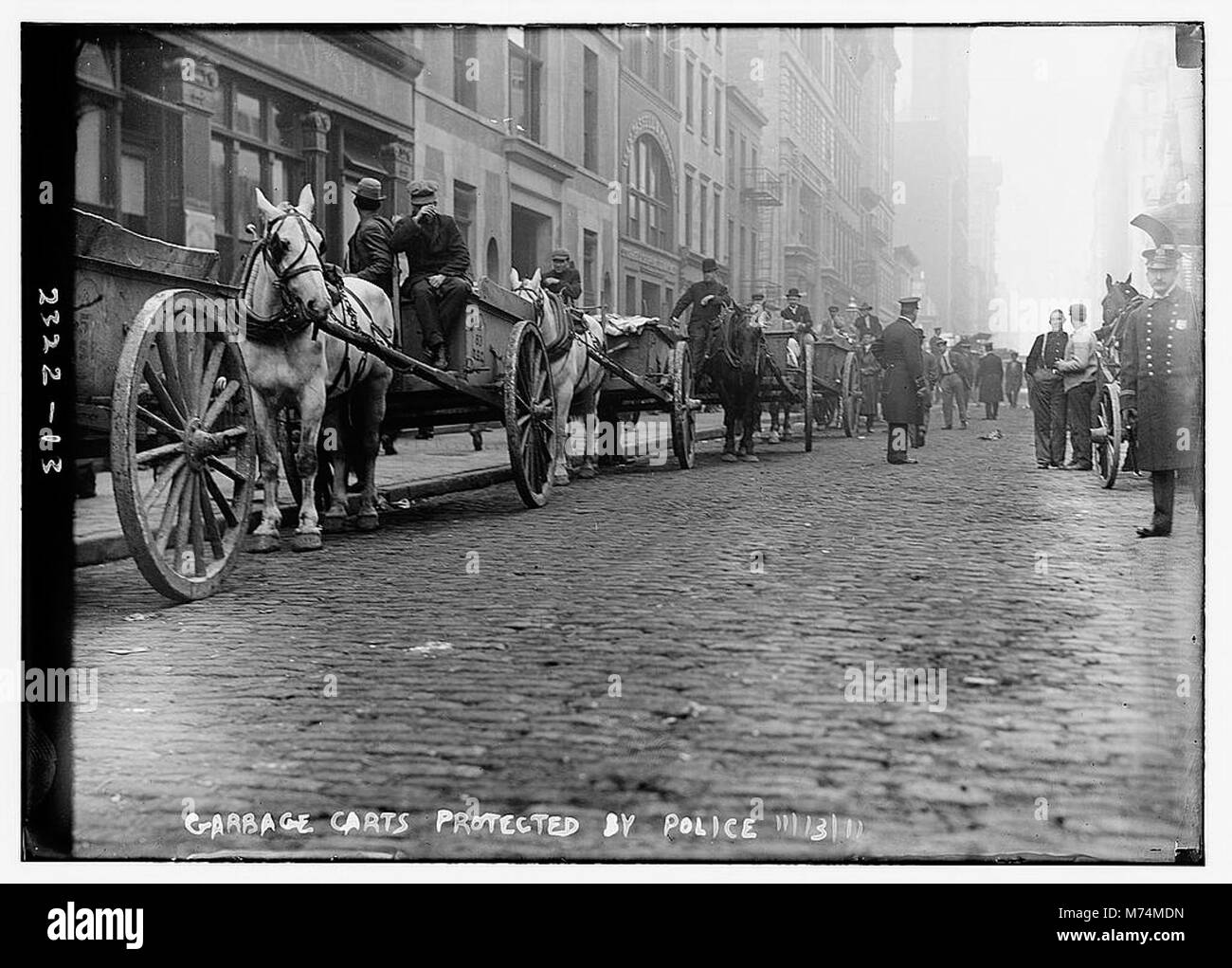 Une image de chariots à ordures protégés par la police, peut-être lors d'un événement public ou d'une grève, capturant un moment unique de l'histoire urbaine. Banque D'Images