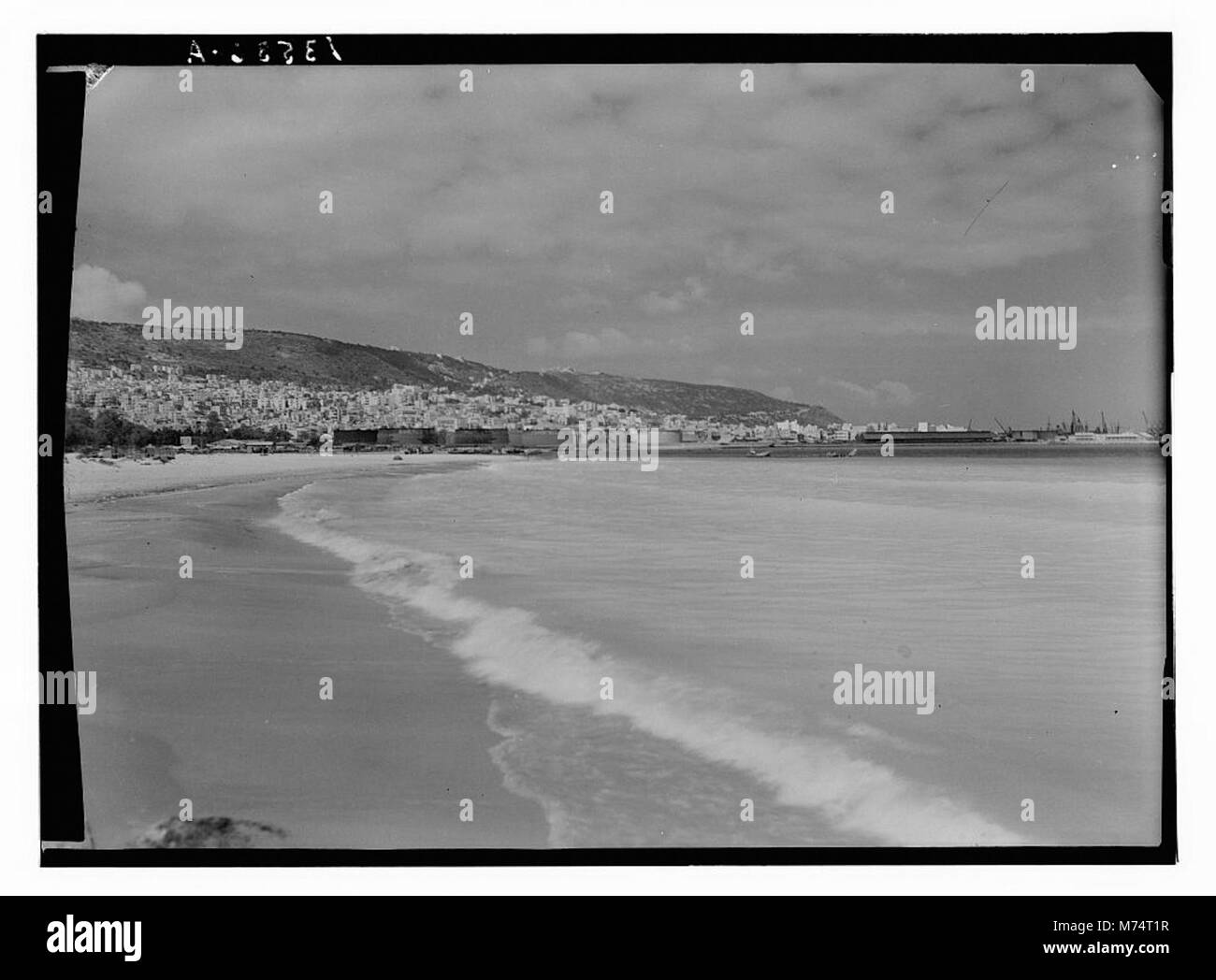 Une vue panoramique depuis la plage de Haïfa, montrant le Mont Carmel au loin. La photographie met en valeur le littoral, la ville et la toile de fond montagneuse. Banque D'Images