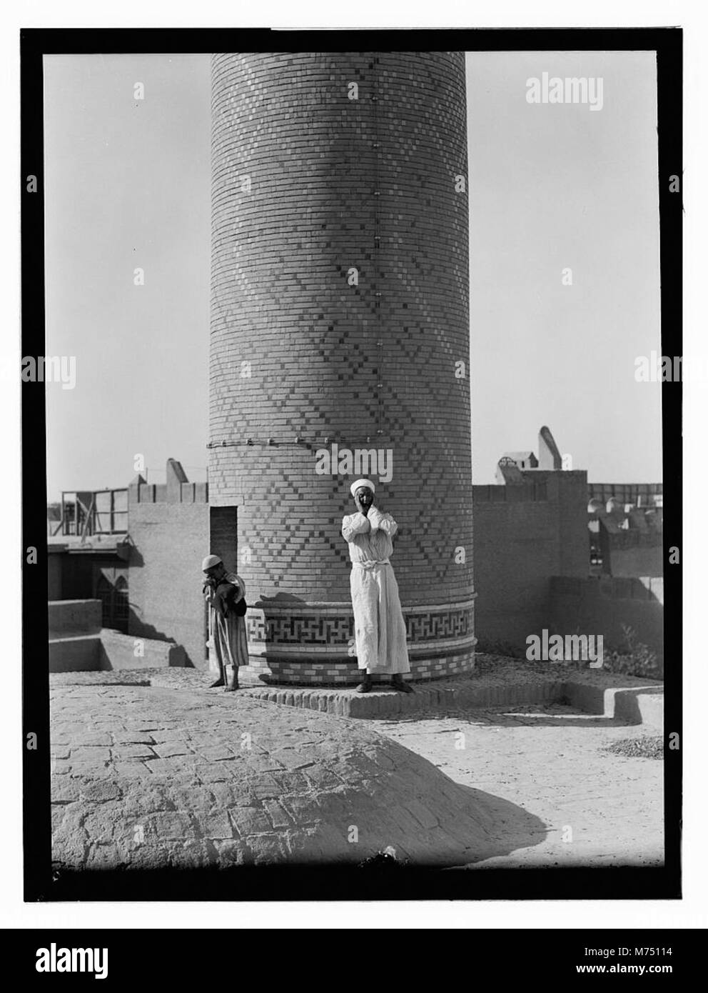 Cette image représente un homme debout à la base d'une colonne en Irak, reflétant l'importance historique et architecturale du site. Banque D'Images