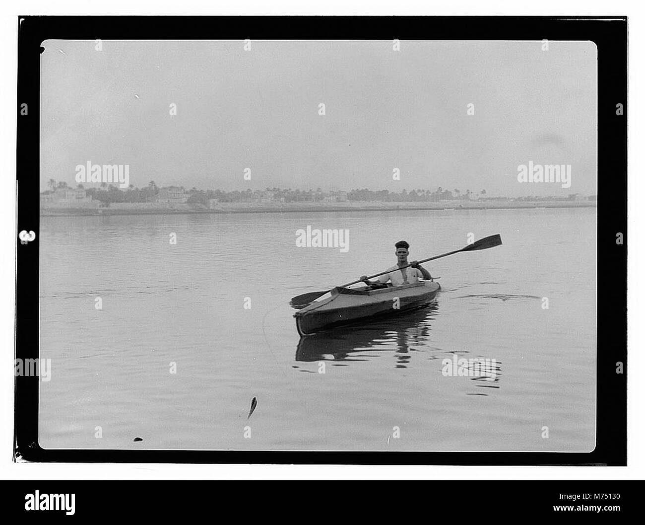 Une image historique de l'Irak montrant Lady Surma, Mr. Pudley, et le révérend John B. Panfil, aux côtés d'un homme ramant un bateau avec une seule rame. Cette image capture un moment dans un paysage étranger. Banque D'Images