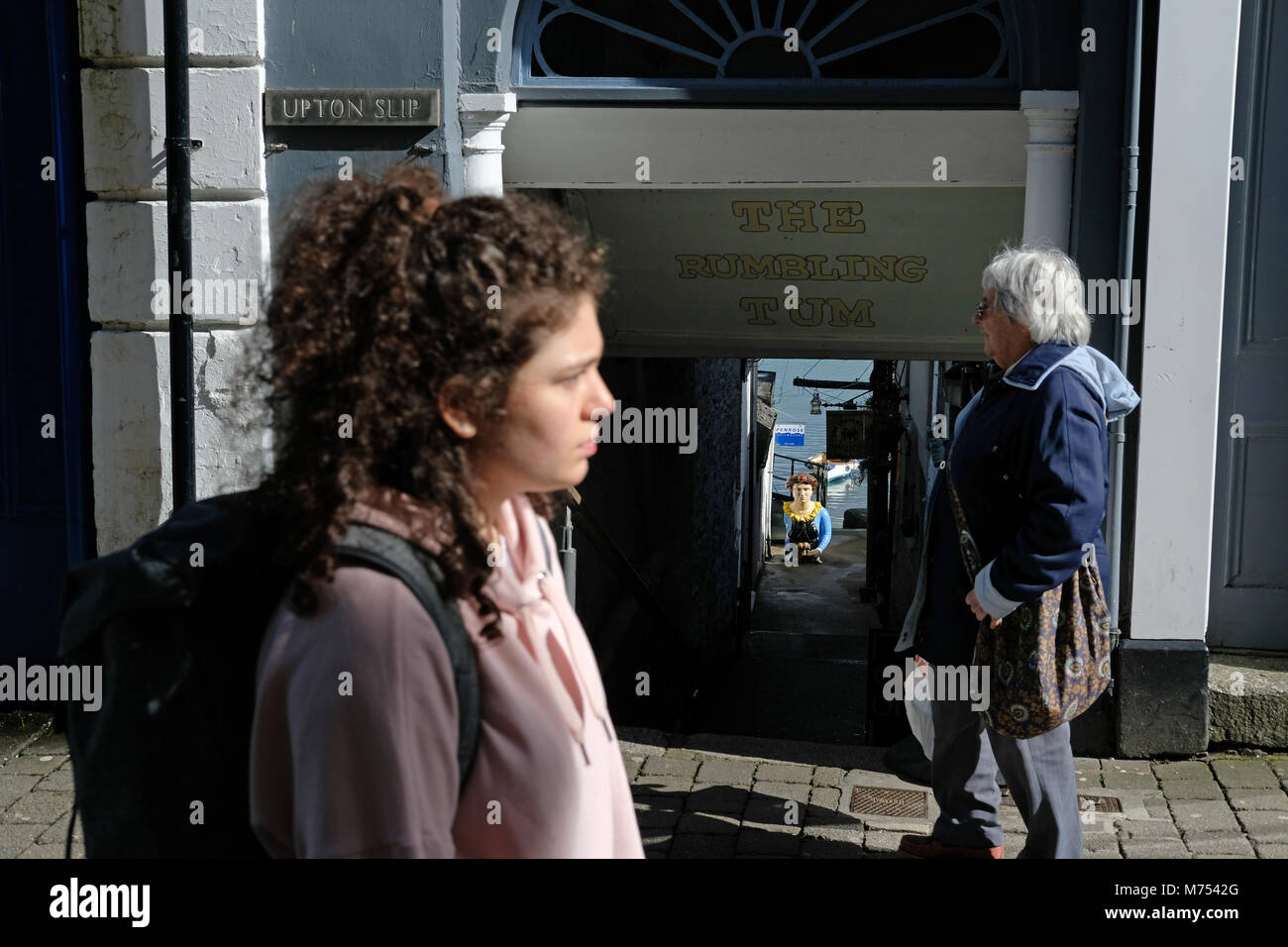 Les gens qui marchent à travers Falmouth avec les navires de proue dans la distance. Banque D'Images