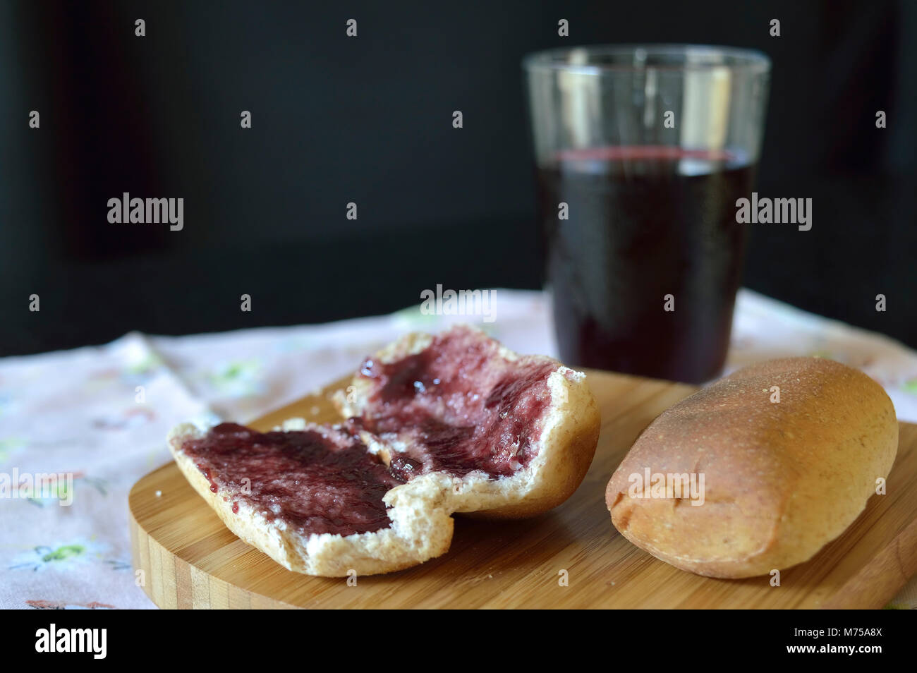 Pain rempli de confiture de petits fruits sur une tablette en bois et certains jus de raisin dans l'arrière-plan Banque D'Images