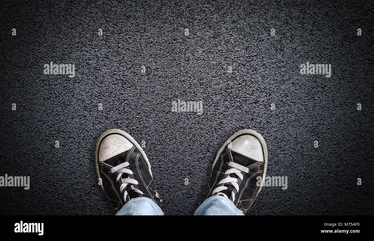 Un adolescent en jeans et chaussures de toile debout sur la route d'asphalte avec copie espace. Concept de debout à la croisée des chemins d'envisager une décision. Banque D'Images