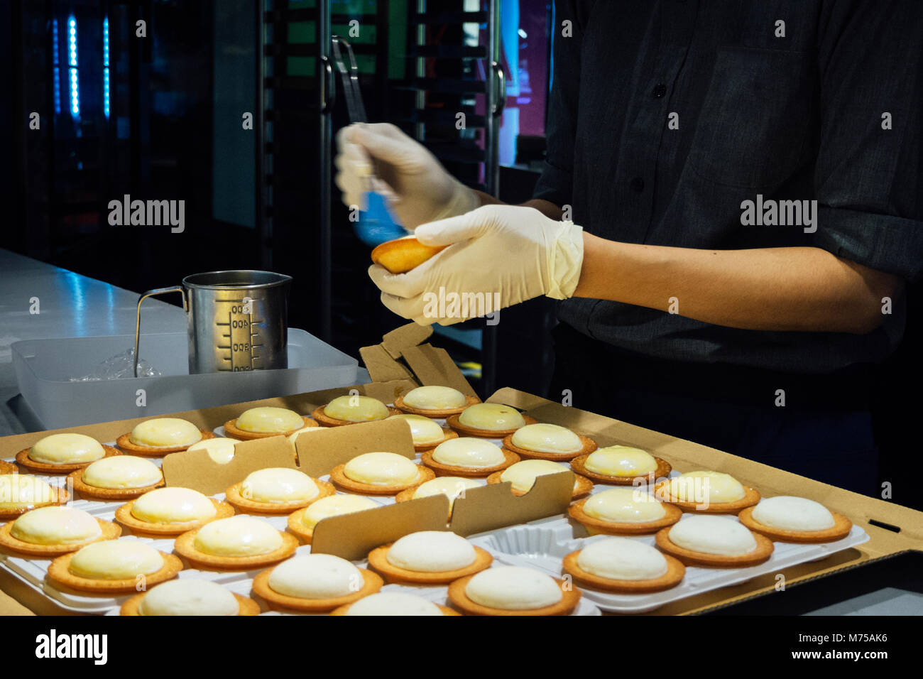 Chef pâtissier femmes prennent un pinceau de brossage et l'oeuf sur le dessus de la tarte de fromage dans la cuisine de la boulangerie. vintage photo et film styl Banque D'Images