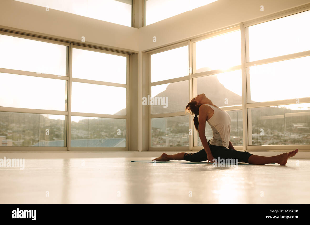Femme souple dans une position de yoga au studio de remise en forme. Femme de faire un split sur un tapis de yoga en salle de sport. Banque D'Images