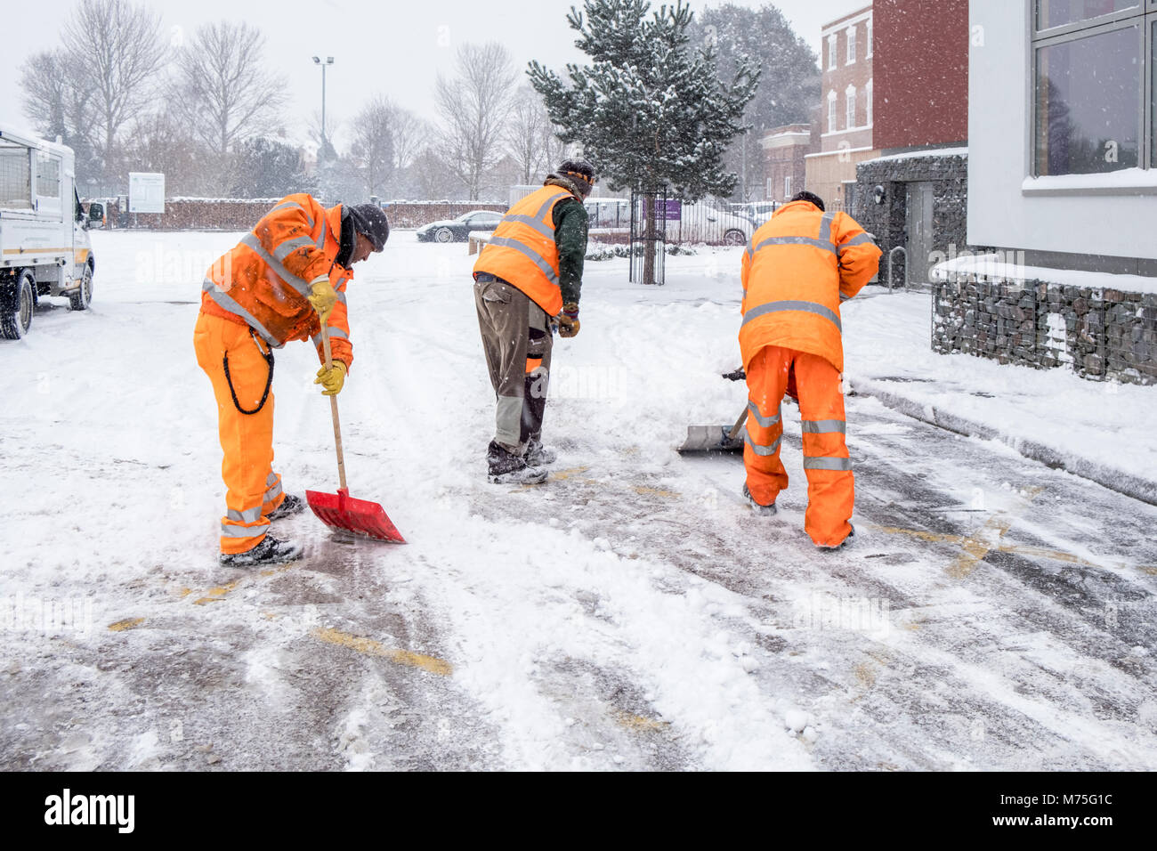 Pelleter la neige Les travailleurs d'une route en parking, West Bridgford, Lancashire, England, UK Banque D'Images