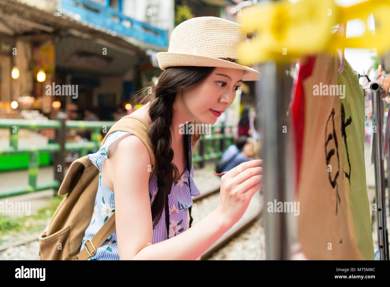 Girl écrit leurs souhaits par écrit à l'aide de pinceau sur le sky lanternes colorées en chinois signifiant l'espoir de bonne fortune Banque D'Images