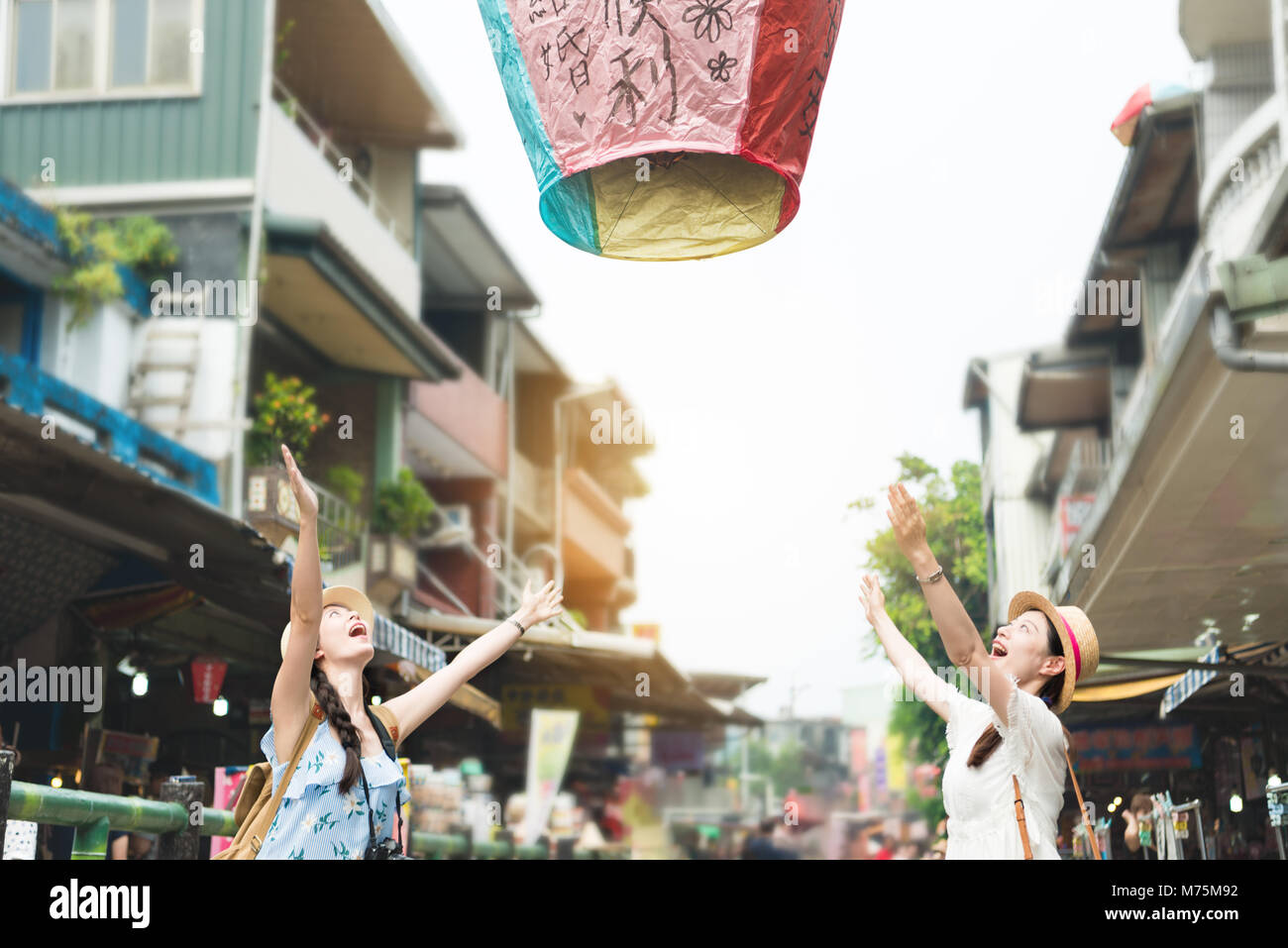 Deux heureux version fille laisser aller les lanternes de ciel à l'air. Traduction sur sky lanterns texte 'l'espoir de bonheur et bonne chance dans l'amour la vie dans l'avenir". Banque D'Images