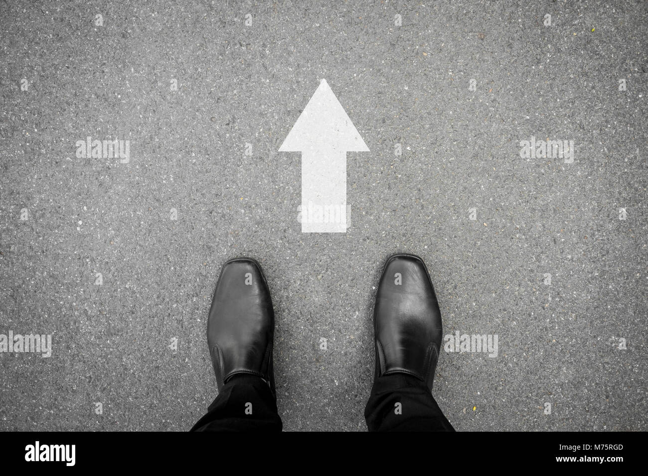 Chaussures noires debout sur le plancher de béton d'asphalte et blanc direction d'aller de l'avant Banque D'Images