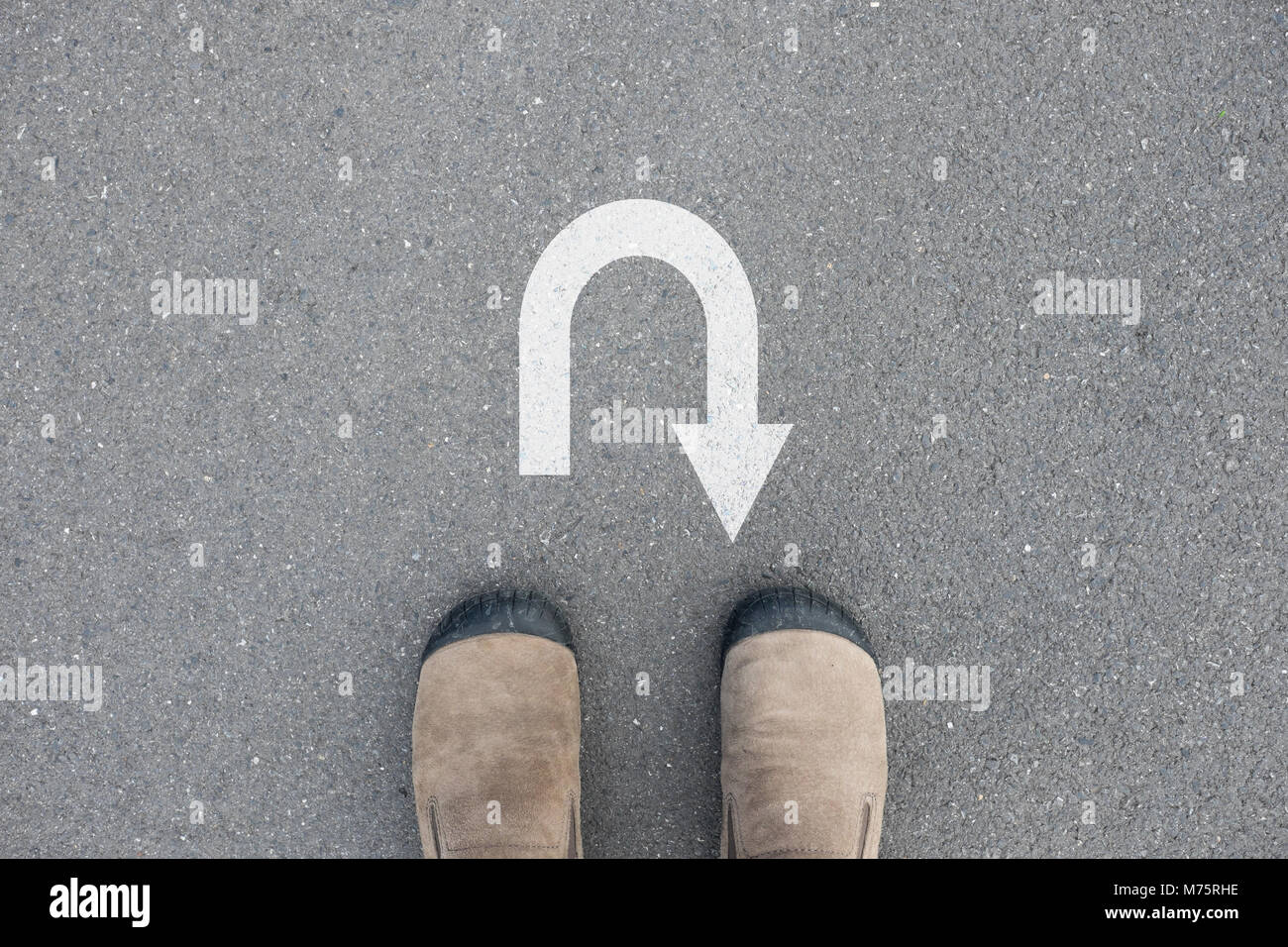 Brown Suede debout sur la route de béton bitumineux en face de U turn sign Banque D'Images
