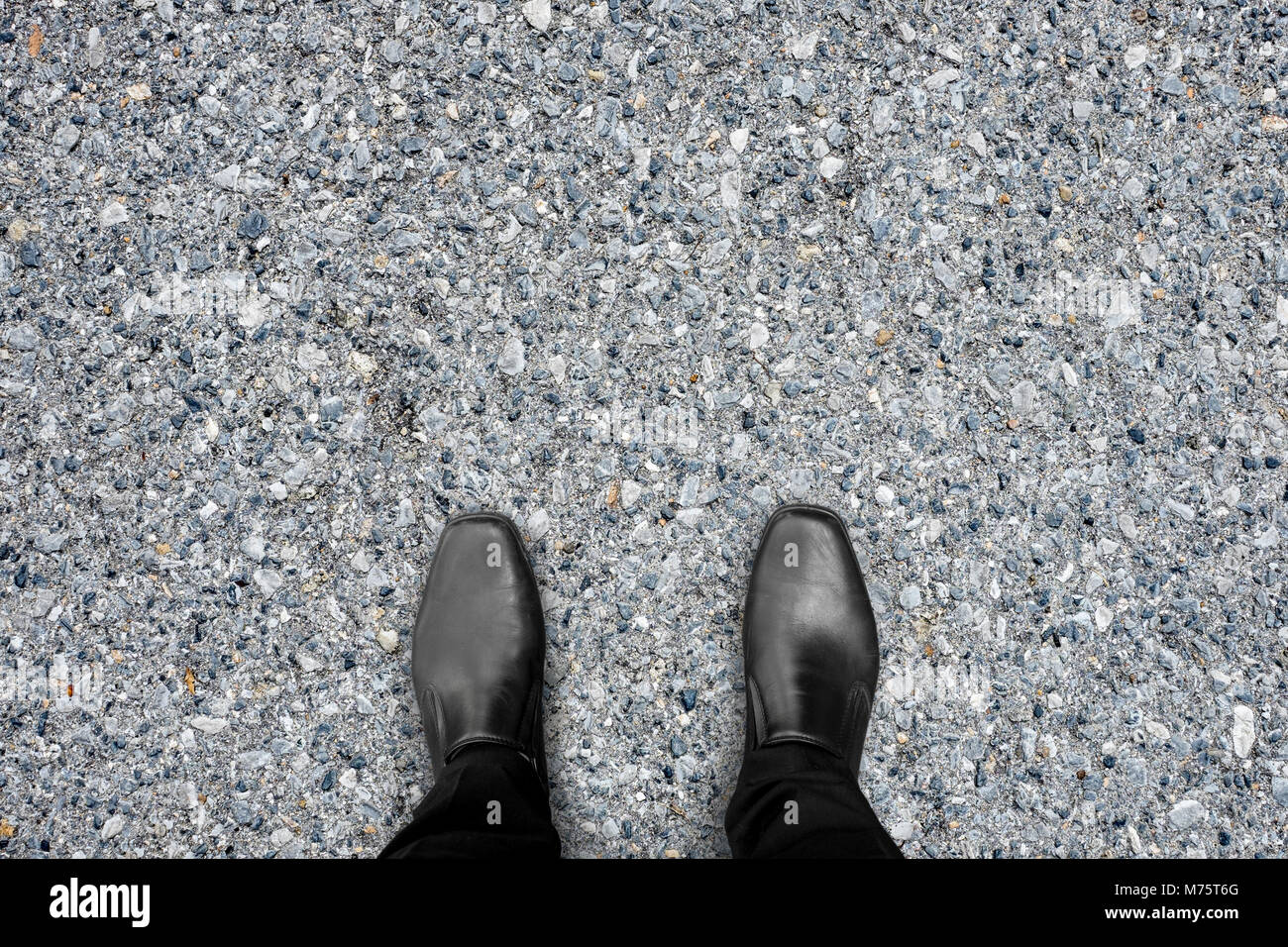 Chaussures noires debout sur le plancher de béton d'asphalte Banque D'Images