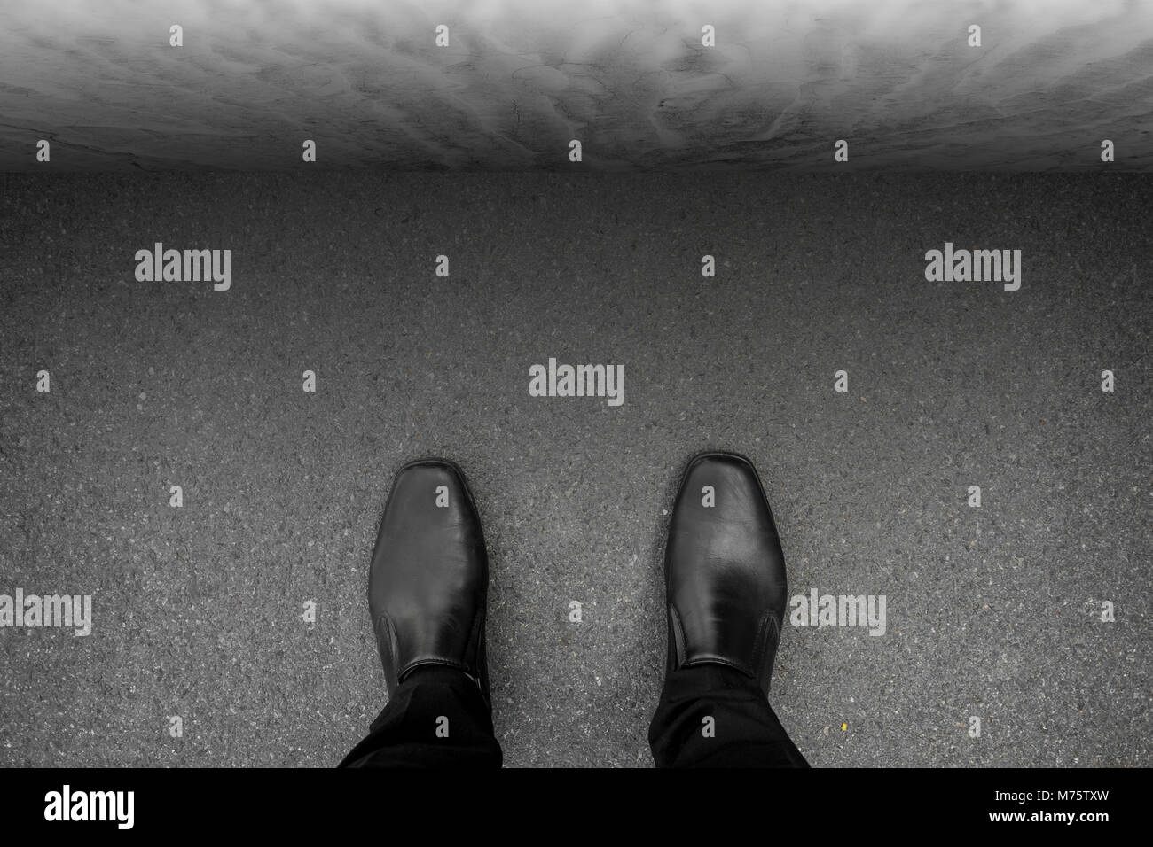 Chaussures noires debout à l'impasse, en face de lui se mur de béton, pas de chemin à faire, pas moyen de sortir. Banque D'Images