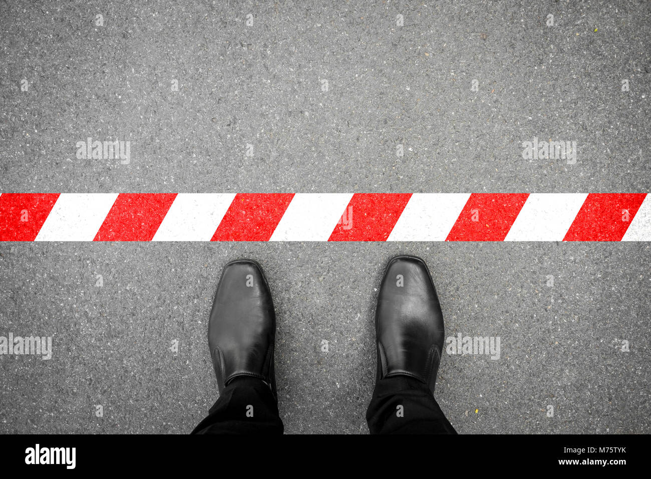 Chaussures noires debout à la ligne rouge-blanc. Ne pas traverser la ligne. C'est interdite et n'est pas autorisé. C'est limité. C'est la fin. Banque D'Images