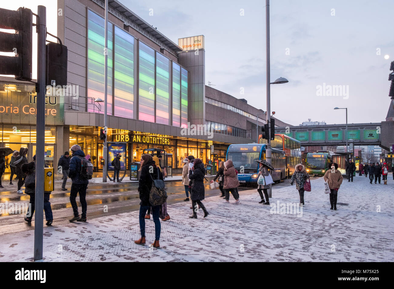 Les gens sur la rue de la ville avec la neige commence à tomber sur une soirée d'hiver, Nottingham, England, UK Banque D'Images