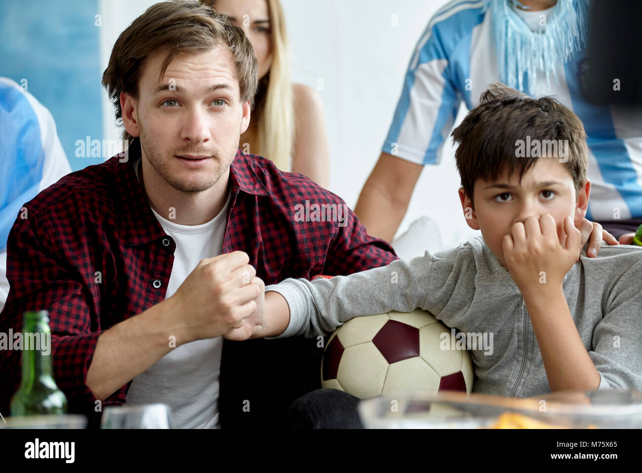 Père et fils se tenant la main tout en regardant des match de foot à la maison Banque D'Images
