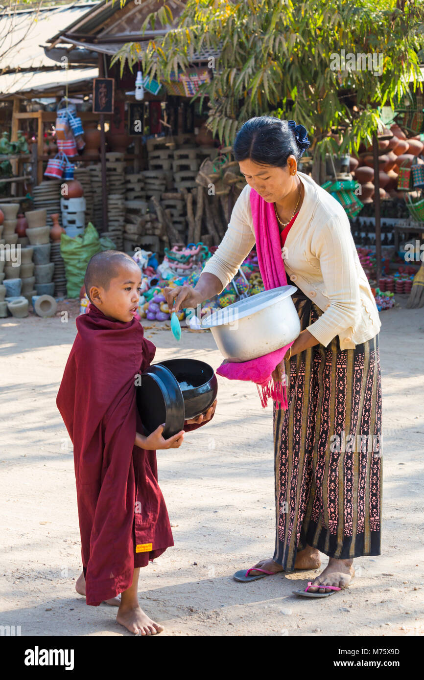 Jeune moine bouddhiste collectant des almes à Bagan, Myanmar (Birmanie), Asie en février - femme locale donnant du riz et de la nourriture Banque D'Images