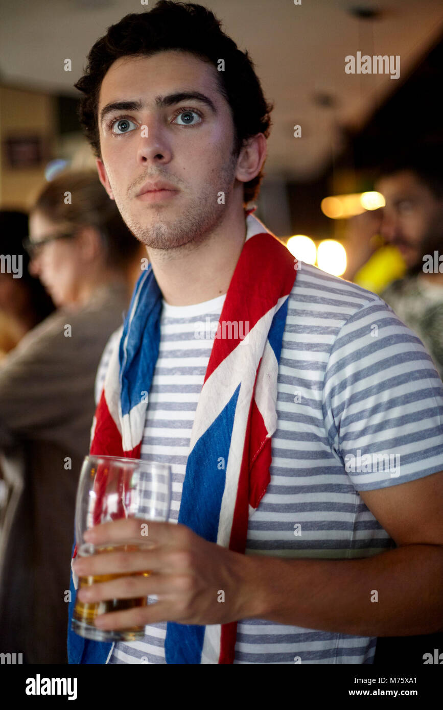 Fan de football britannique regarder match en bar avec drapeau drapé autour du cou Banque D'Images