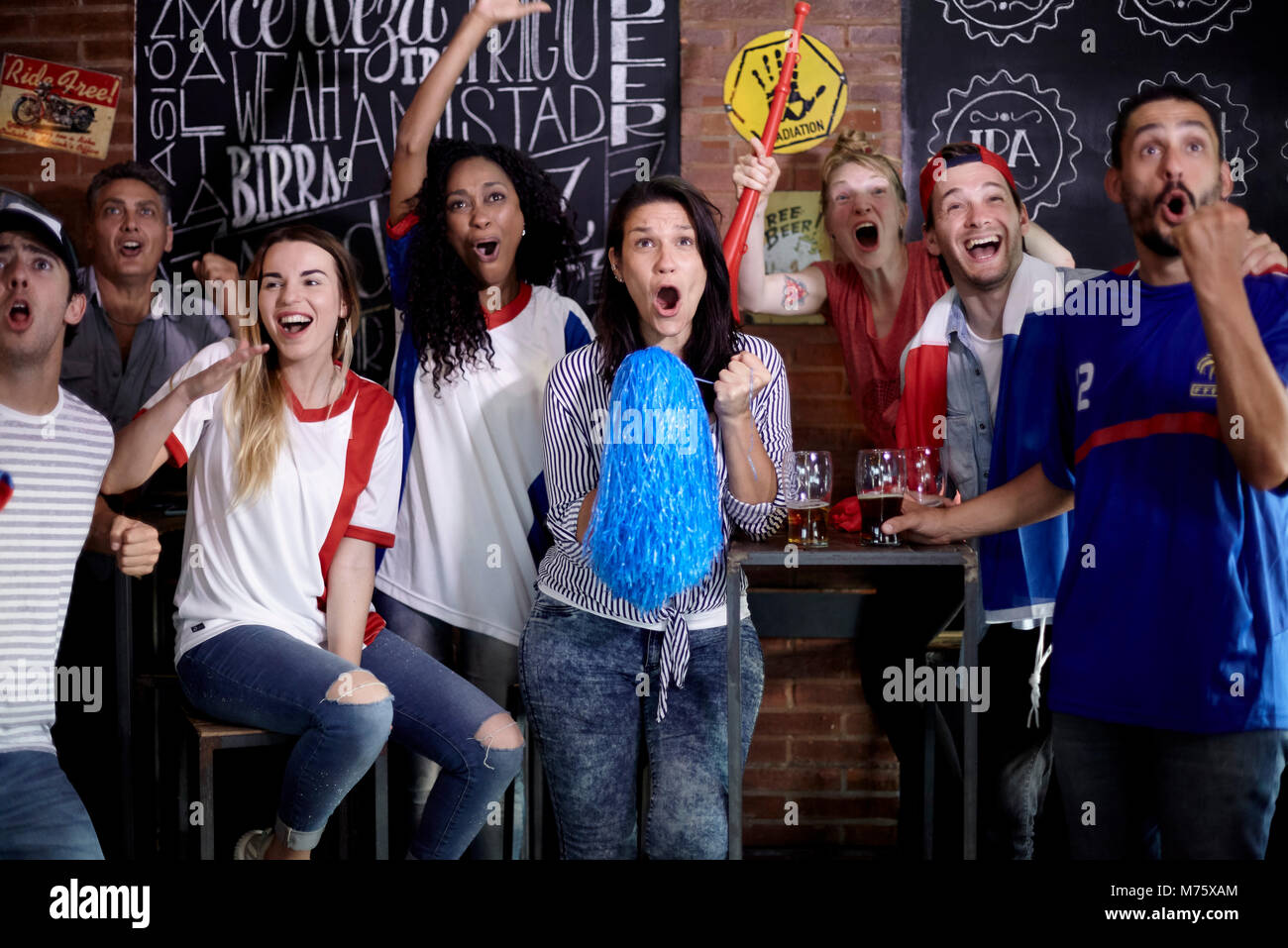 Les amateurs de sport célébrant la victoire en regardant match à bar Banque D'Images