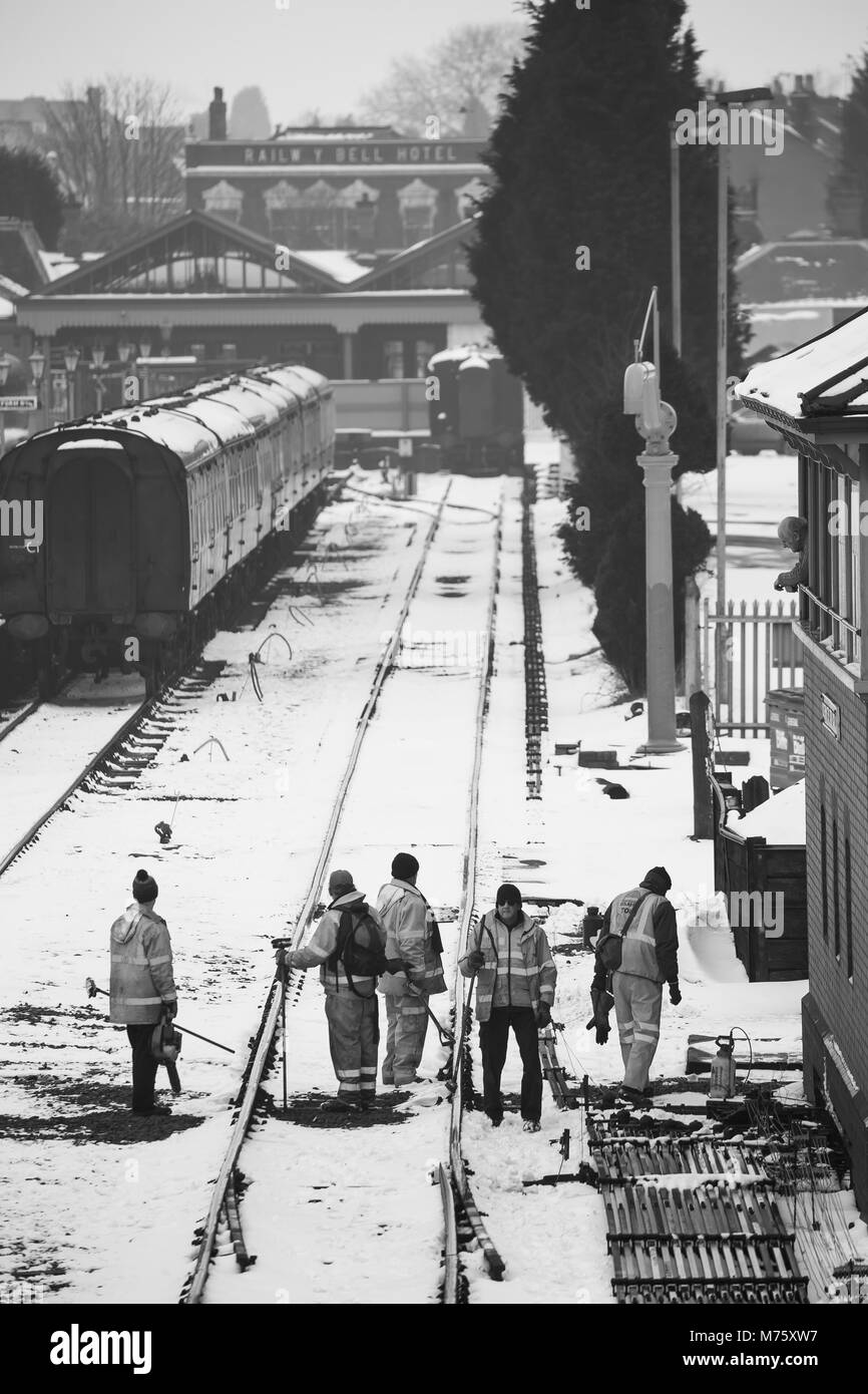 Scène en noir et blanc, gare de Severn Valley Kidderminster dans la neige. Les employés des chemins de fer se sont dégagtés de la ligne pour s'assurer qu'elle est à la pointe de la vapeur ! Travail d'équipe Royaume-Uni. Banque D'Images