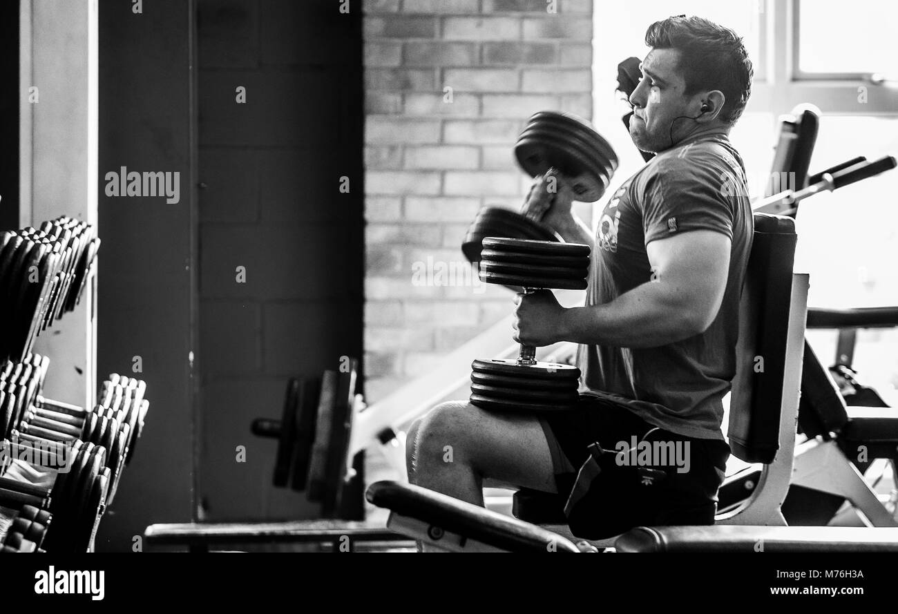 Homme travaillant sur musculaire avec des poids dans la salle de sport Banque D'Images