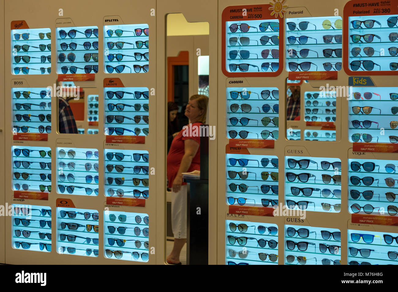 Une vieille femme à la recherche de l'optique à miroir en magasin à Yas Mall Banque D'Images