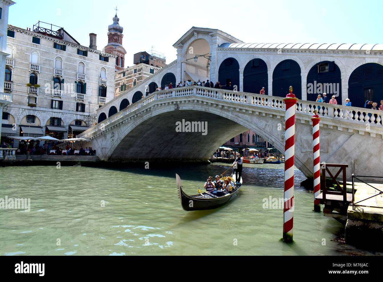 Une télécabine passant sous le pont du Rialto, Sestiere San Polo, Venise, l'agglomération de la ville de Venise, Italie, avec rouge et blanc à rayures bollards. Banque D'Images