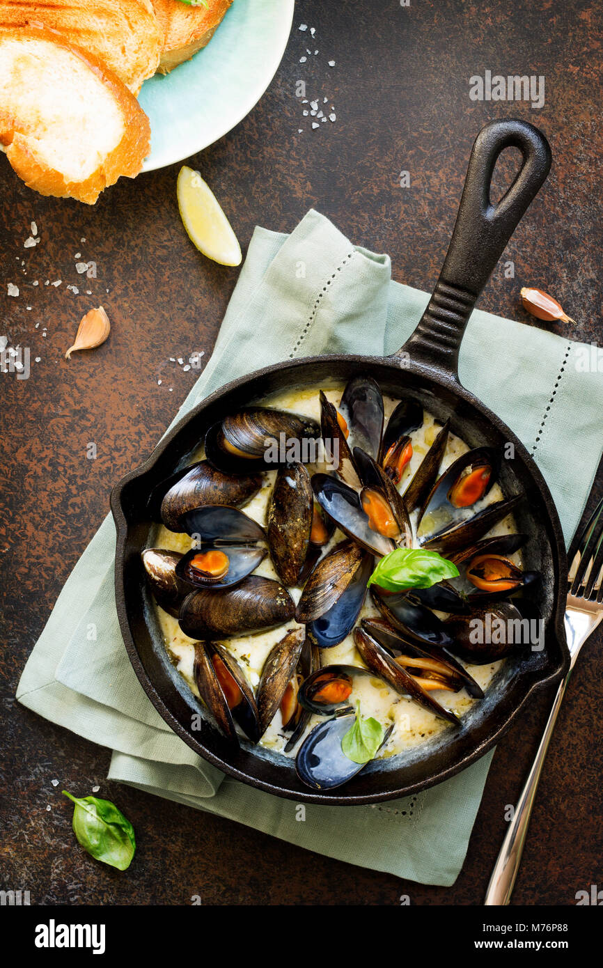 Les moules cuites dans une sauce de vin blanc, servi avec pain grillé et citron. La cuisine gastronomique italienne. Banque D'Images