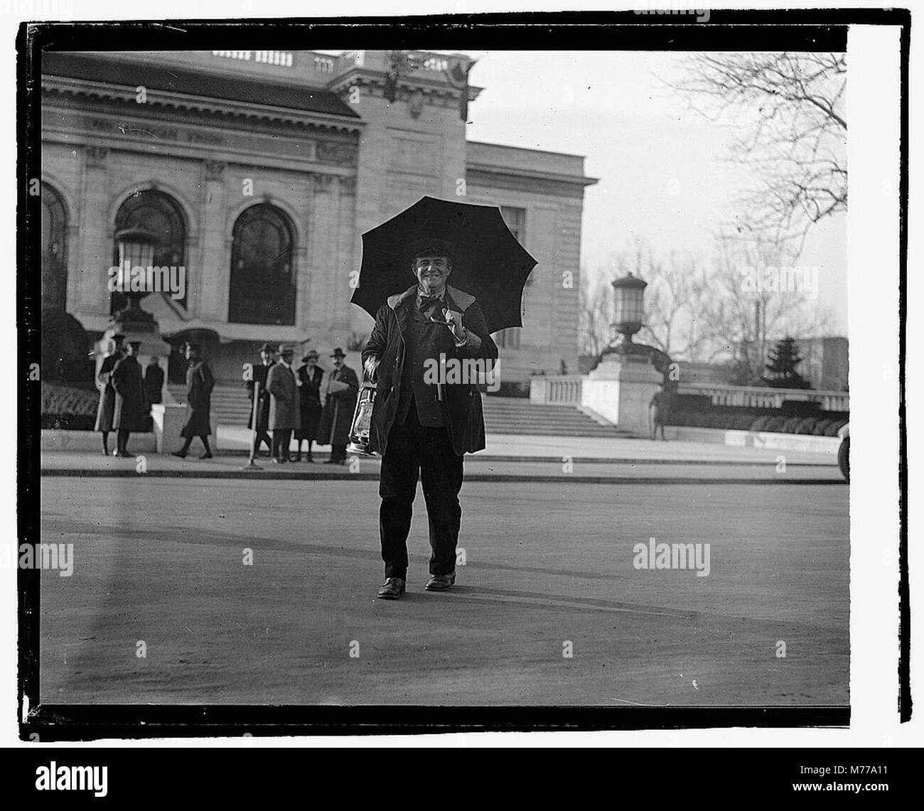 Photographie d'un homme non identifié tenant un parapluie, debout dans une rue avec un bâtiment en arrière-plan, datée du 15 décembre 1921. Banque D'Images