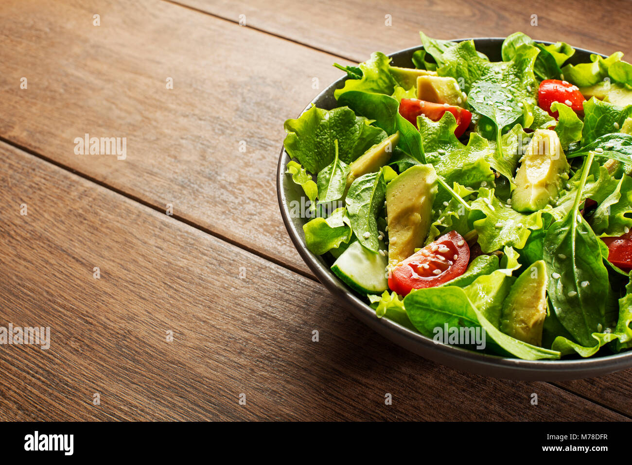 Salade de laitue verte à l'avocat et des légumes frais sur fond de bois. Banque D'Images