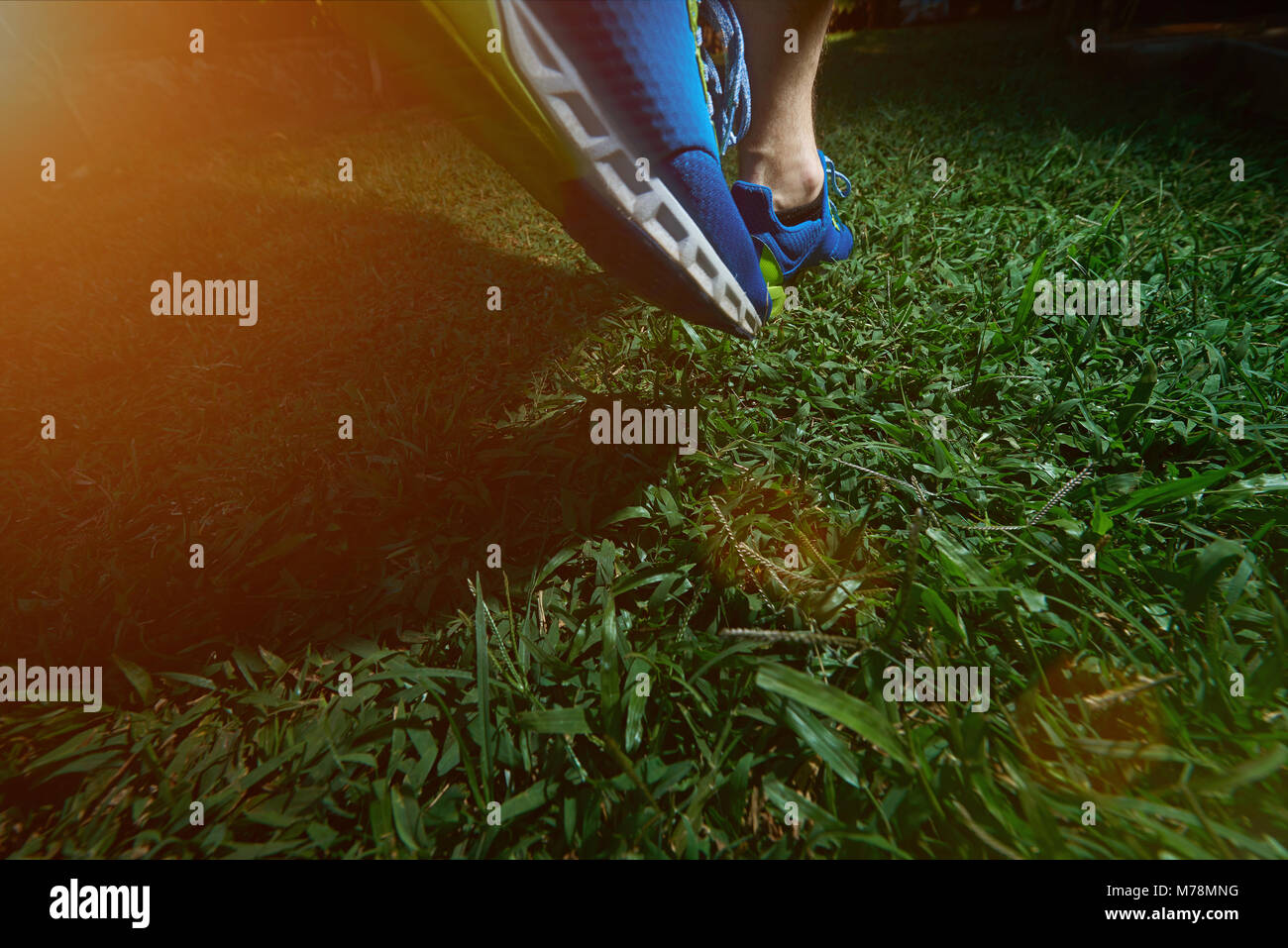 Man jogging sur terrain herbe verte en bleu chaussures. Close-up de l'étape de l'homme Banque D'Images
