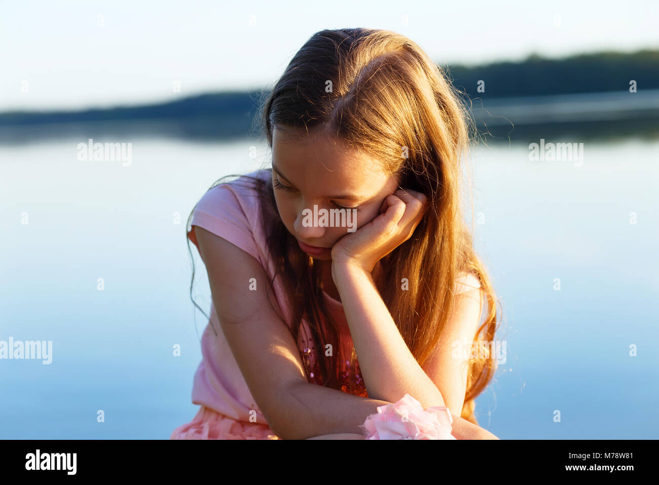 Triste belle fille de l'adolescence est à la recherche de visage sérieux au bord de mer au coucher du soleil. Banque D'Images