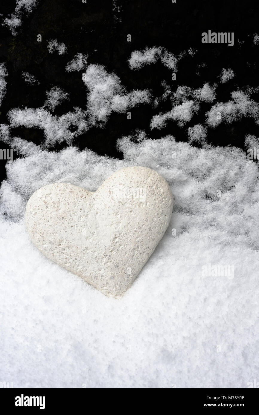 Coeur fait main placée contre ardoises pour toiture sur laquelle la neige est retombée, la création d'un paysage en minature imitant la neige qui tombe à travers un ciel sombre Banque D'Images